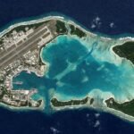 Aerial view of Diego Garcia military base showing runways and naval ships.