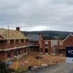A construction site for new homes in the UK with scaffolding and a for sale sign.