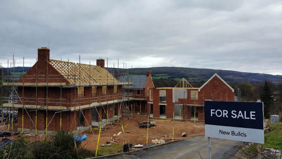 A construction site for new homes in the UK with scaffolding and a for sale sign.